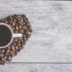 coffee beans in a heart shape with a mug of black coffee sitting on top